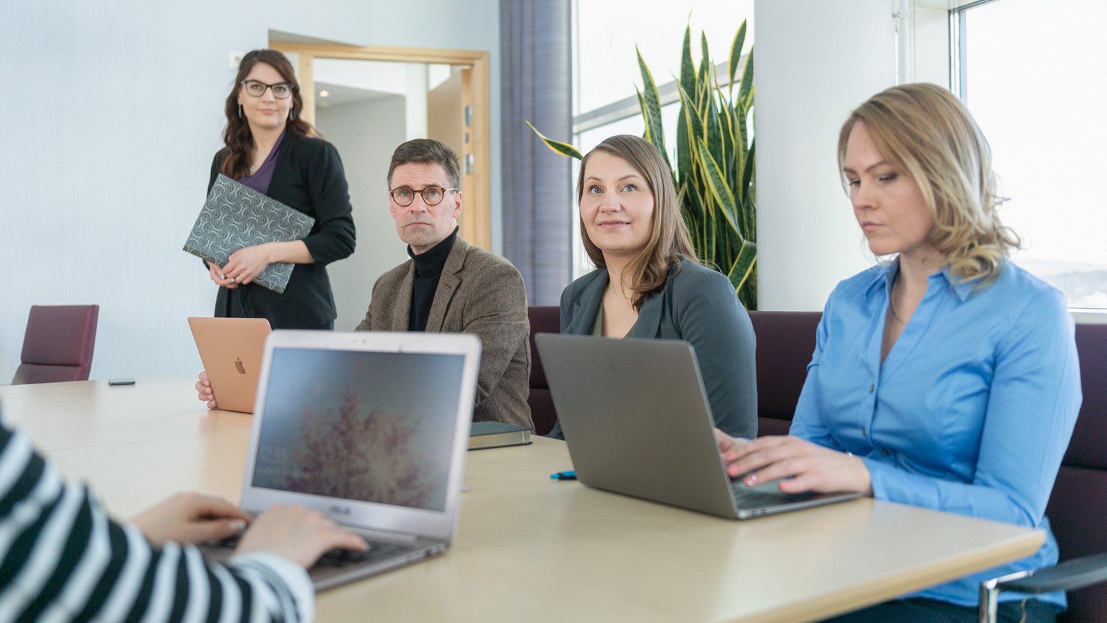 Eri rooleista rakennettu Mavenfirstin asiantuntijatiimi kokoontuneena toimistoon tietokoneiden kanssa ja suunnittelemassa asiakkaan tilanteen ratkaisua.